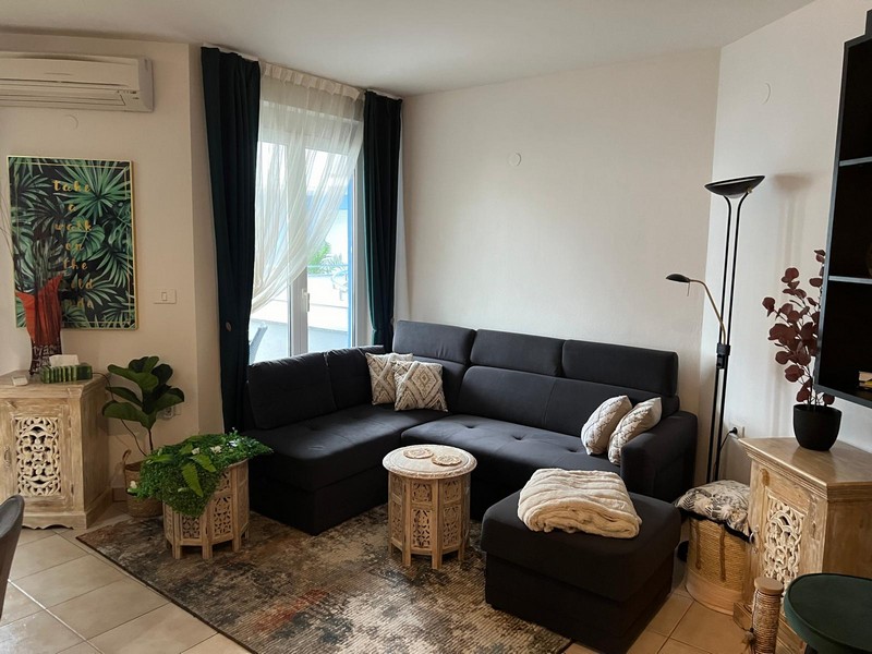 Canapé d'angle foncé avec tapis devant la fenêtre du salon