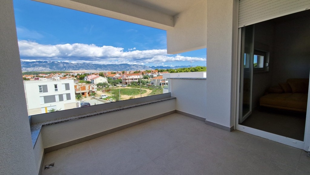 Vue du balcon d'un appartement à Novalja, île de Pag, avec vue mer et environnement urbain, biens immobiliers Croatie