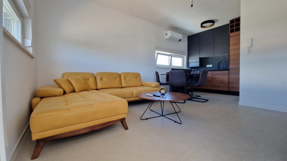Intérieur d'un appartement à Novalja, île de Pag, à l'aménagement moderne et avec un canapé jaune, biens immobiliers Croatie