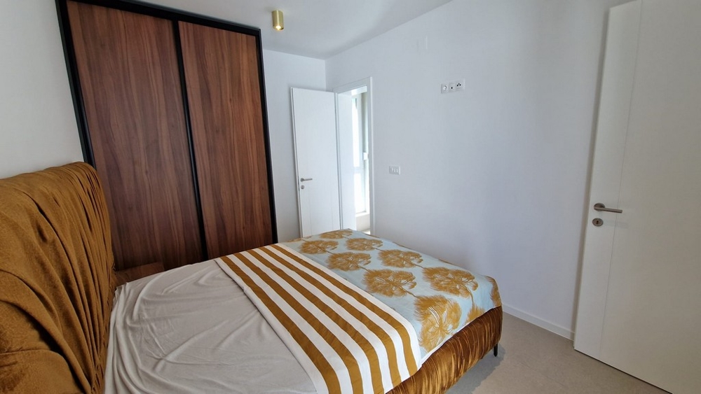Chambre d'un appartement à Novalja, île de Pag, avec linge de lit rayé et éléments en bois, biens immobiliers Croatie