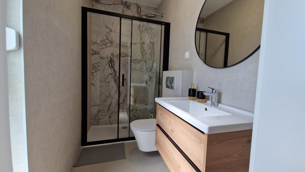 Salle de bains d'un appartement à Novalja, île de Pag, avec robinetterie moderne et douche en marbre, biens immobiliers Croatie
