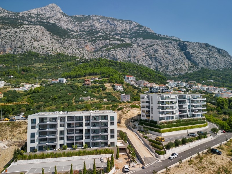 Biens immobiliers en Croatie, Makarska, appartement avec vue mer : vue aérienne de deux immeubles résidentiels modernes le long d'une route