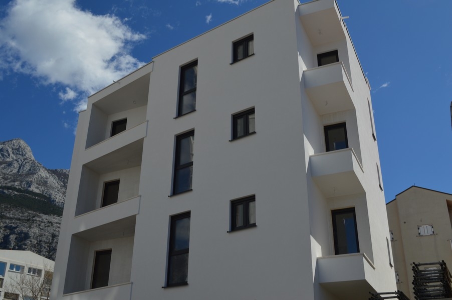 Immeuble neuf blanc avec loggias devant la chaîne de montagnes