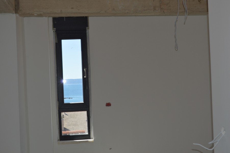 Fenêtre étroite dans un appartement inachevé avec vue mer.