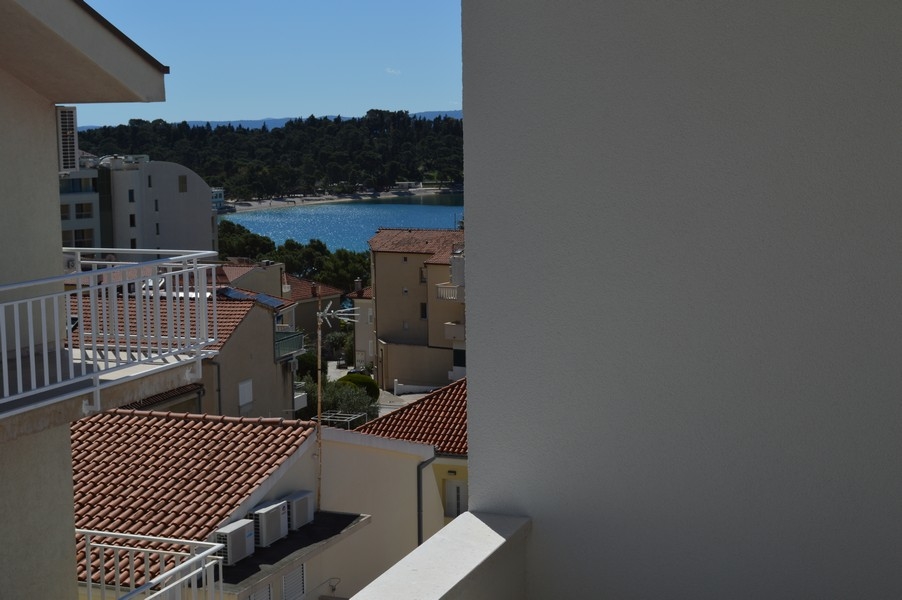 Vue mer partiellement masquée depuis un balcon d'un appartement inachevé.
