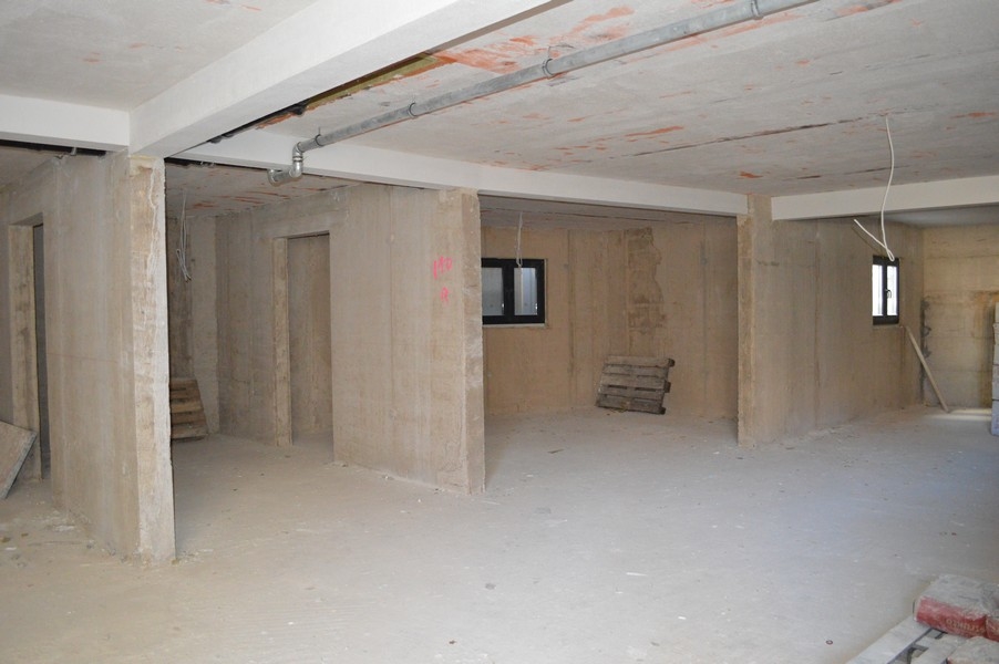 Pièce inachevée au sous-sol avec murs et sols en béton, prévue pour des places de parking en garage.