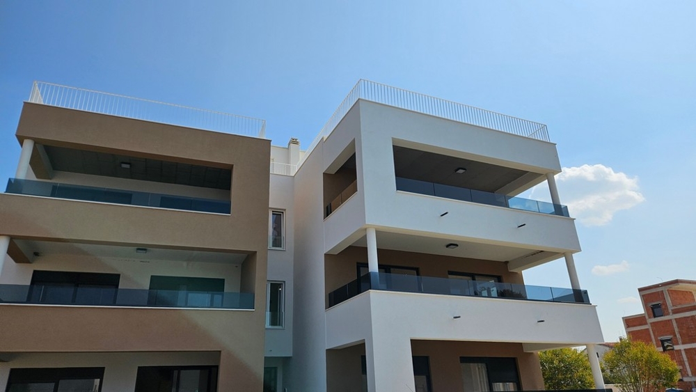Deux constructions neuves avec balcons en verre et toits-terrasses