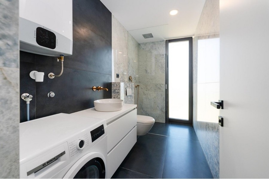 Salle de bains avec lave-linge, lavabo blanc, douche en verre