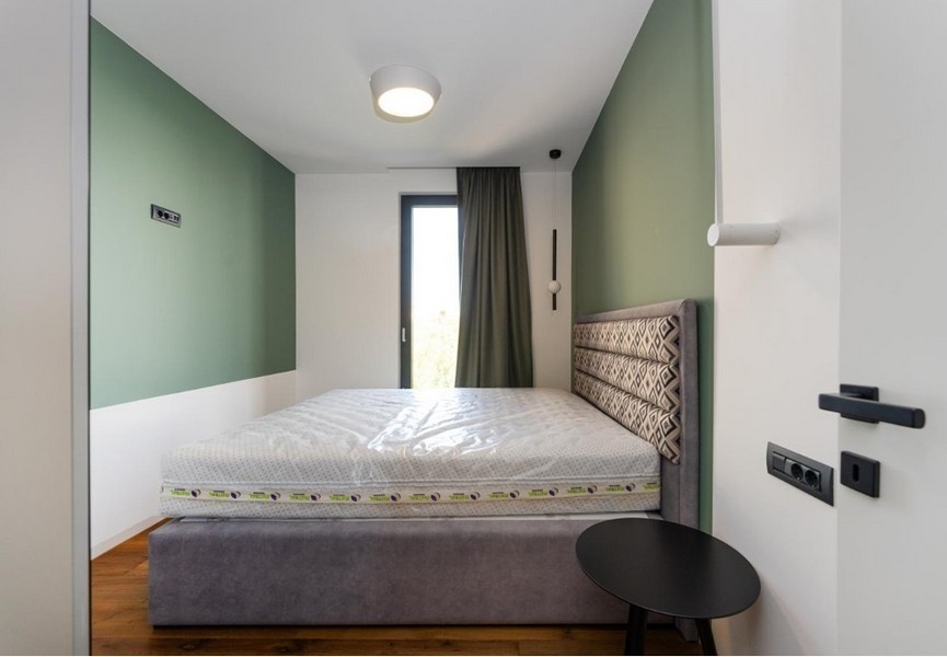 Chambre avec murs vert et blanc, cadre de lit gris