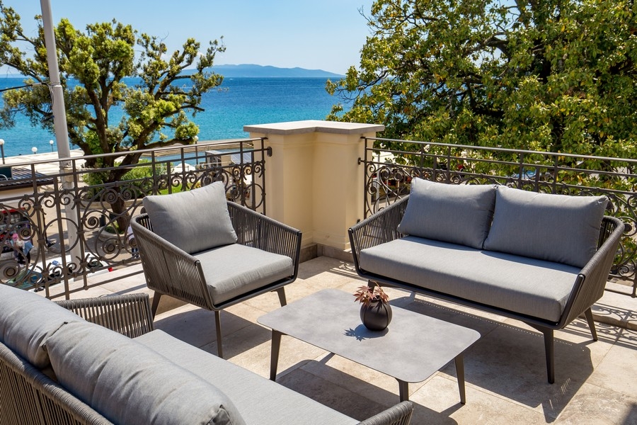 Terrasse avec mobilier lounge derrière une rambarde en fer forgé