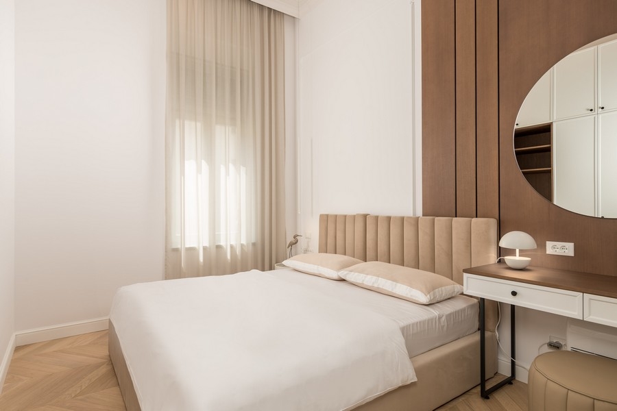Chambre avec lit beige et bureau