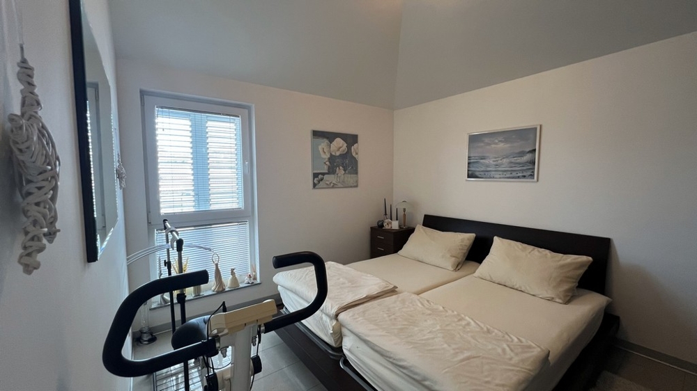 Chambre avec deux lits simples, vélo d'appartement et aménagement minimaliste.