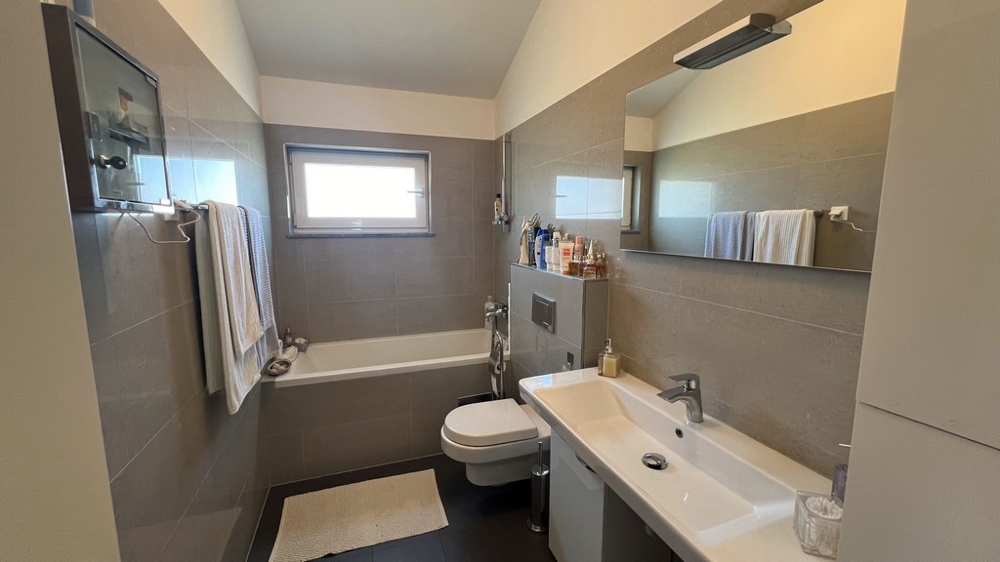 Salle de bains moderne avec baignoire, lavabo et WC, aménagement sobre et lumineux.