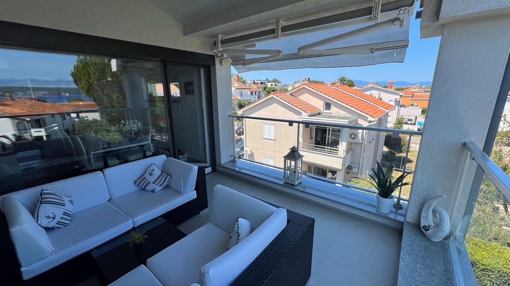 Terrasse avec vue sur la mer et les maisons voisines, équipée de canapés blancs et de coussins décoratifs marins.