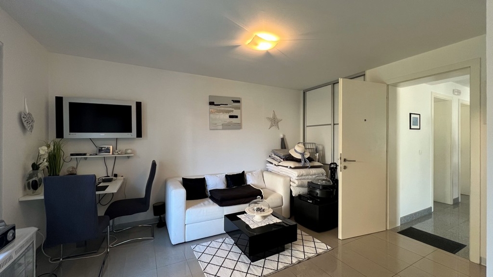 Séjour convivial du studio au rez-de-chaussée avec canapé, bureau et télévision.