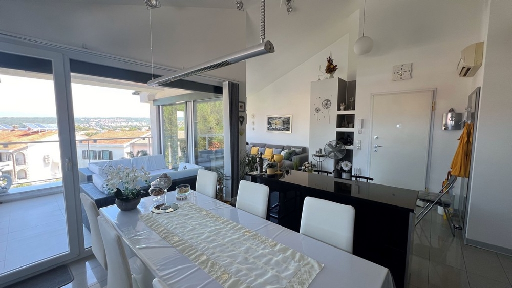 Coin repas et cuisine avec meubles modernes, grande façade vitrée donnant sur la terrasse avec vue mer.