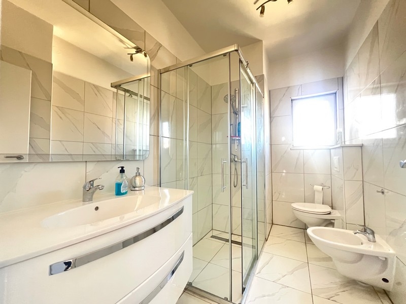 Salle de bains soignée avec fenêtre et beaucoup de lumière.