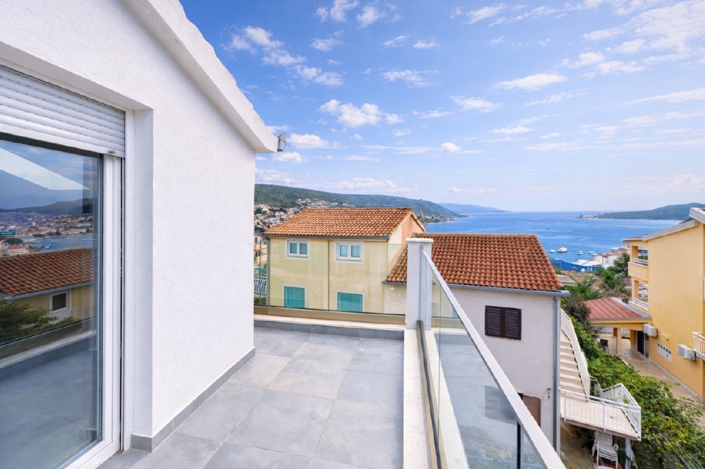 Toit-terrasse avec garde-corps en verre au-dessus des toits de tuiles en bord de mer