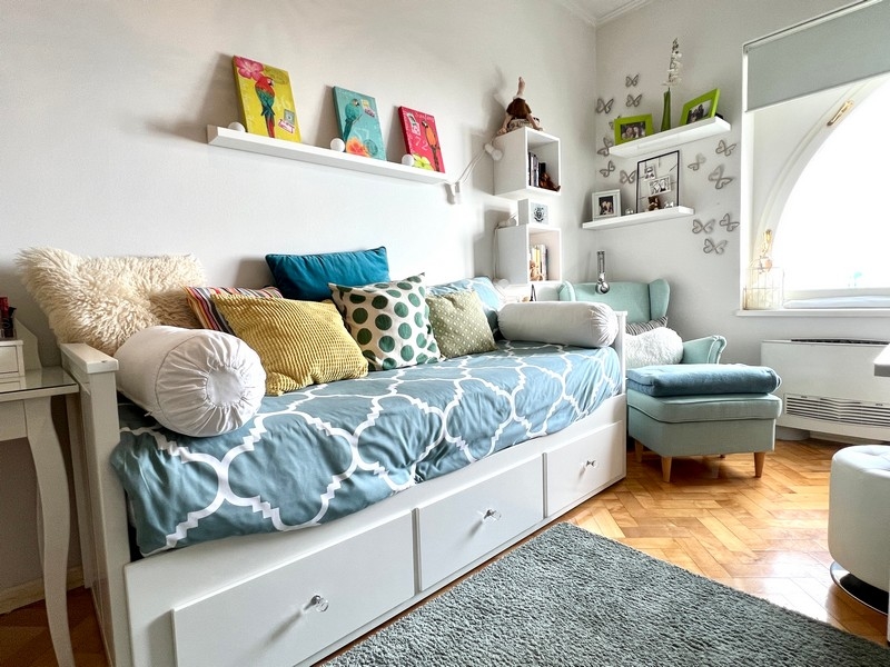 Chambre d'amis avec lit de jour, coussins décoratifs et coin salon agréable