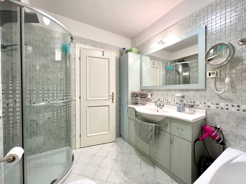 Salle de bains avec douche, grand miroir et carrelage blanc