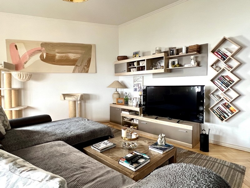 Salon avec canapé gris, téléviseur à écran plat et étagères décoratives