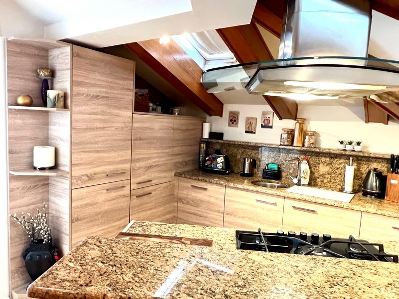 Vue de la cuisine avec plans de travail en granit et appareils modernes