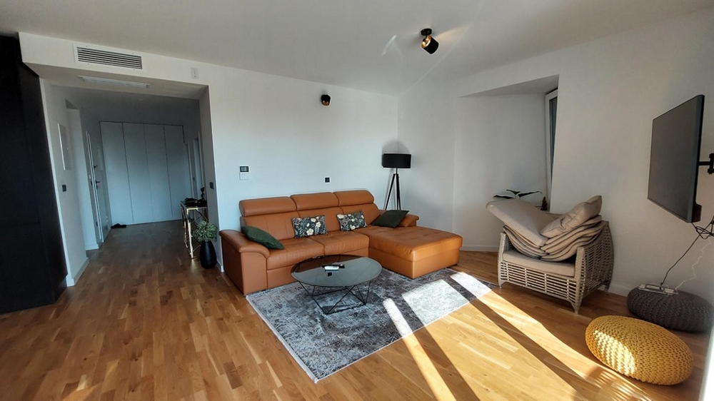 Salon avec canapé en cuir, parquet et vue sur le couloir