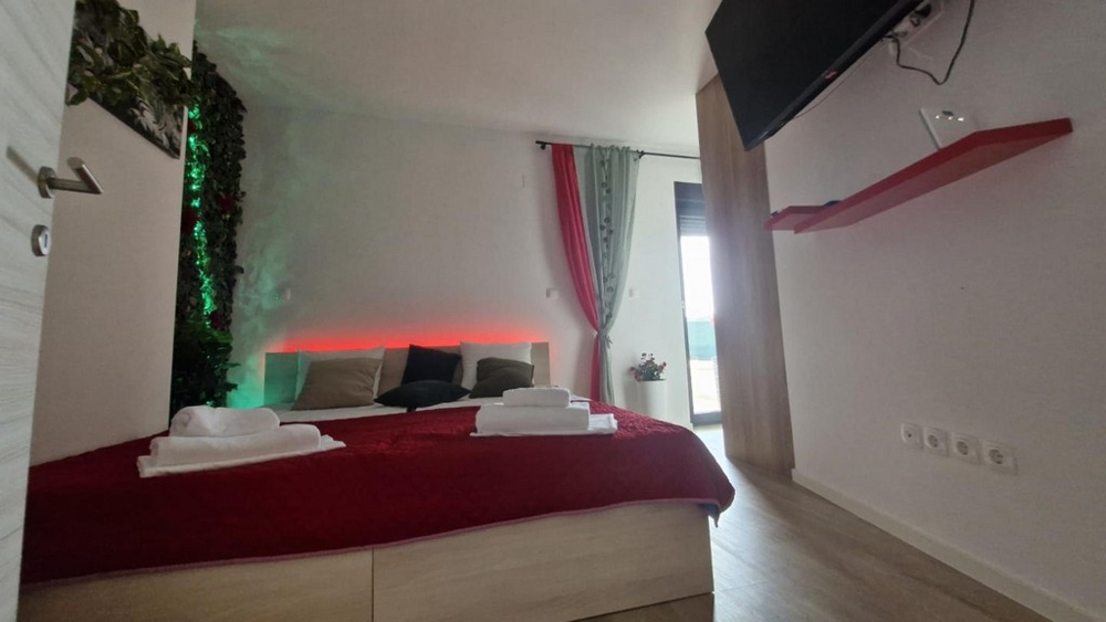 Chambre avec couette rouge, fond décoratif et télévision au mur
