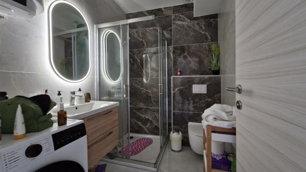 Salle de bains avec douche, lavabo et lave-linge