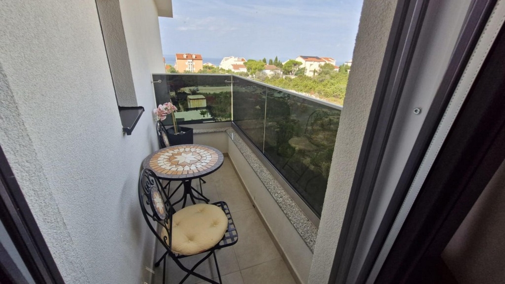 Balcon avec petite table et deux chaises, vue sur les bâtiments voisins