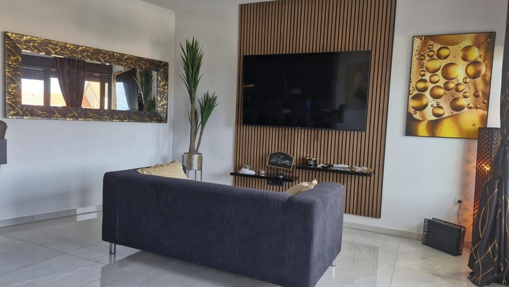 Salon avec grande télévision, canapé et éléments décoratifs