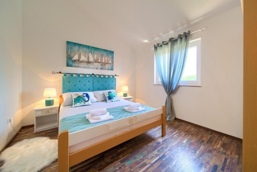 Chambre avec lit double, tête de lit turquoise et éléments de décoration maritimes