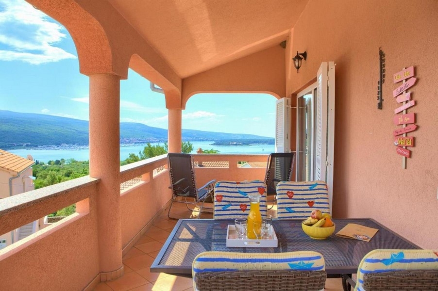 Terrasse couverte avec table et chaises, vue mer à l'arrière-plan