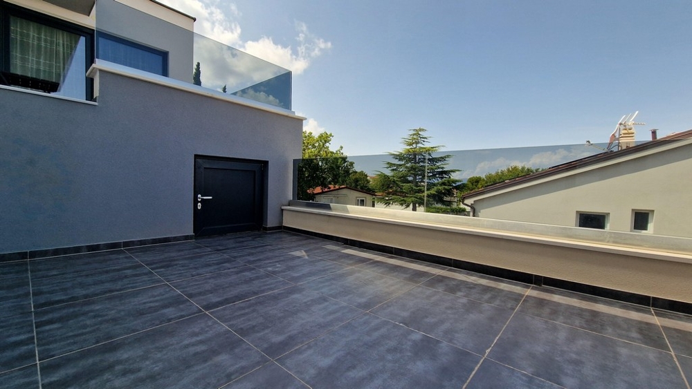 Terrasse au carrelage foncé devant la porte d'entrée