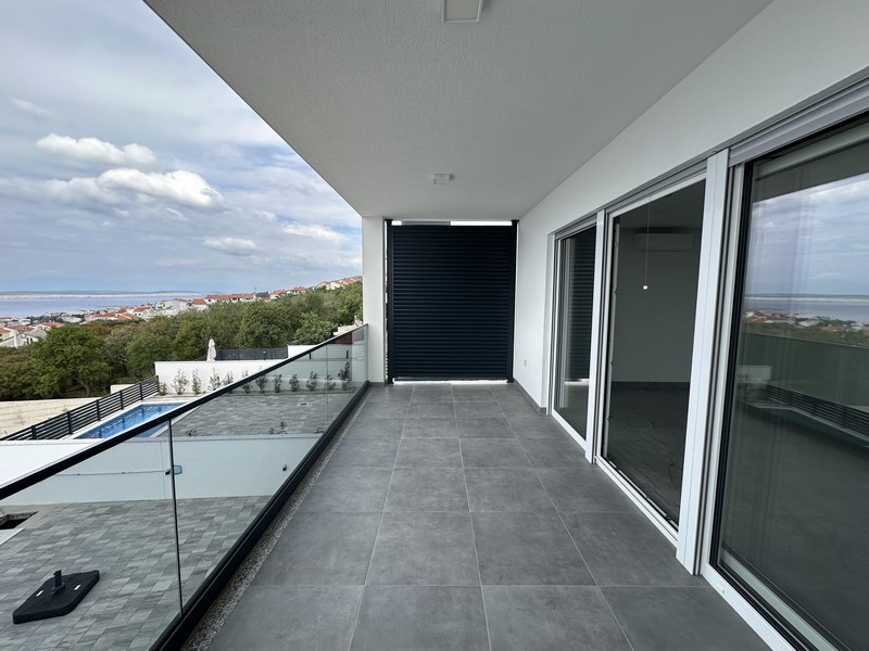 Longue loggia avec garde-corps en verre et vue sur la piscine et la mer