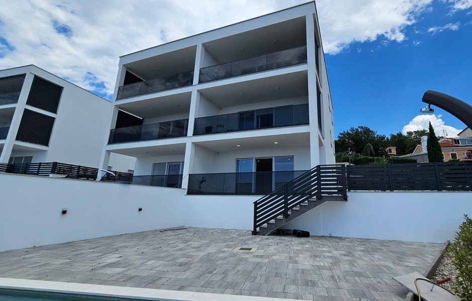 Immeuble neuf avec trois niveaux de balcons au-dessus de l'espace piscine