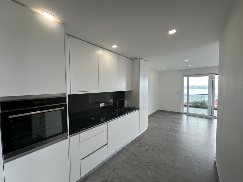 Cuisine blanche moderne avec séjour ouvert et vue sur la mer