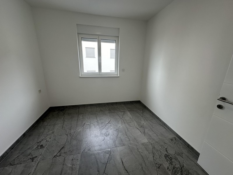 Deuxième chambre vide avec sol carrelé et une fenêtre