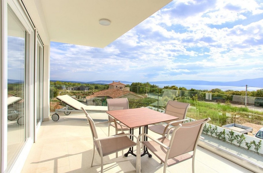 Terrasse avec table et chaise longue devant la vaste vue sur la baie