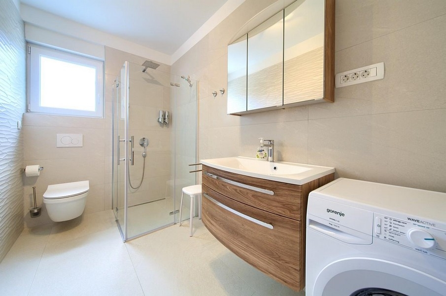 Salle de bains moderne avec douche et lave-linge.