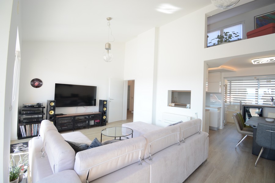 Séjour lumineux avec canapé et mezzanine au-dessus du coin repas