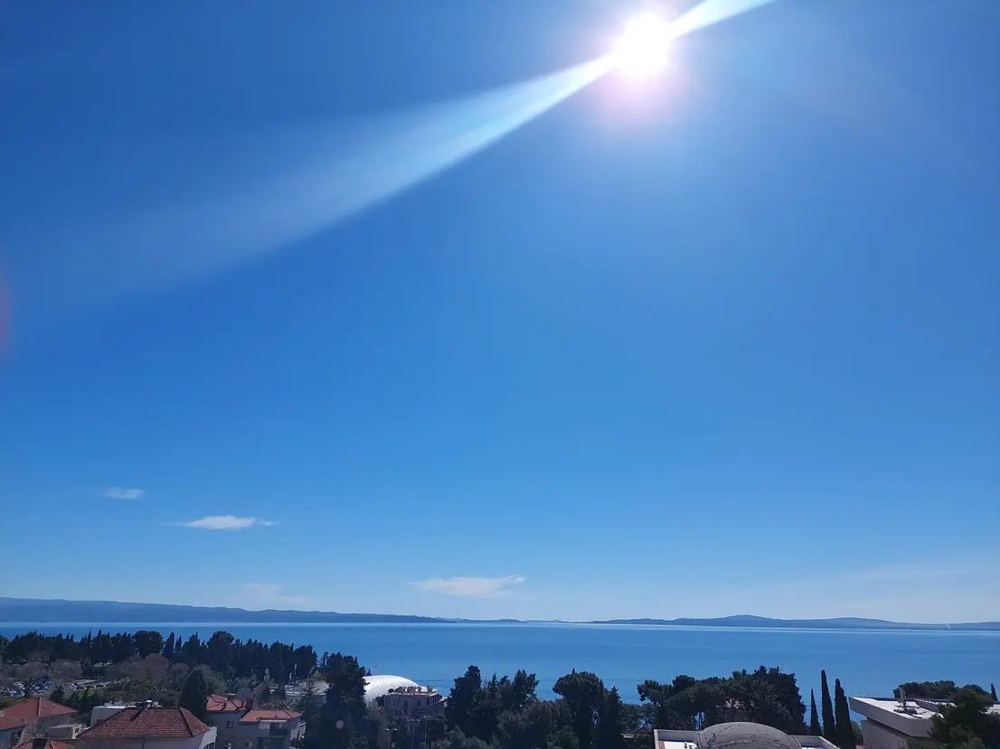 Soleil au-dessus de la baie avec cyprès et toits en contrebas