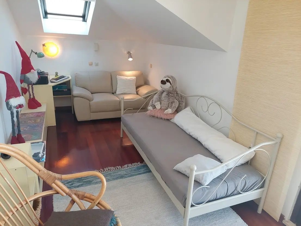 Pièce avec lit, canapé, fenêtre de toit et décoration, y compris des peluches