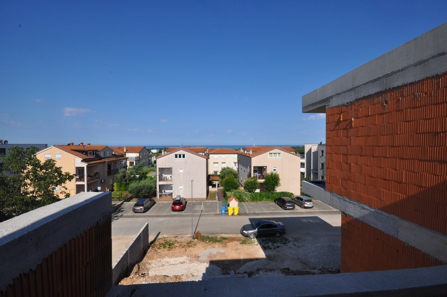 Vue depuis le gros œuvre sur les places de stationnement et les maisons jusqu'à la mer