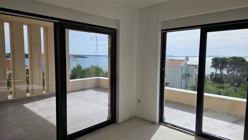 Séjour avec grandes baies vitrées montrant la vue mer et le balcon