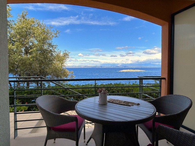 Table de balcon avec fauteuils en rotin et vue sur le petit îlot