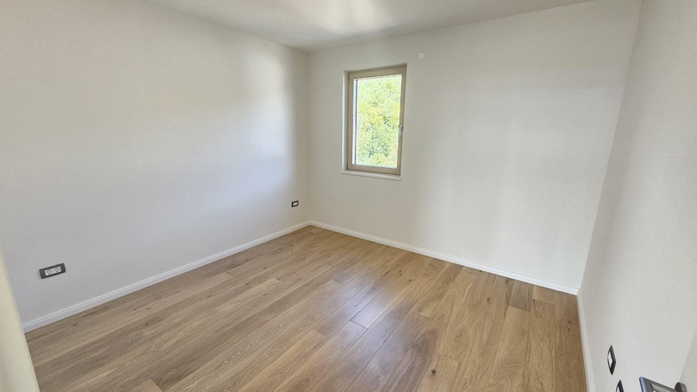 Chambre lumineuse avec parquet et vue par la fenêtre sur la verdure