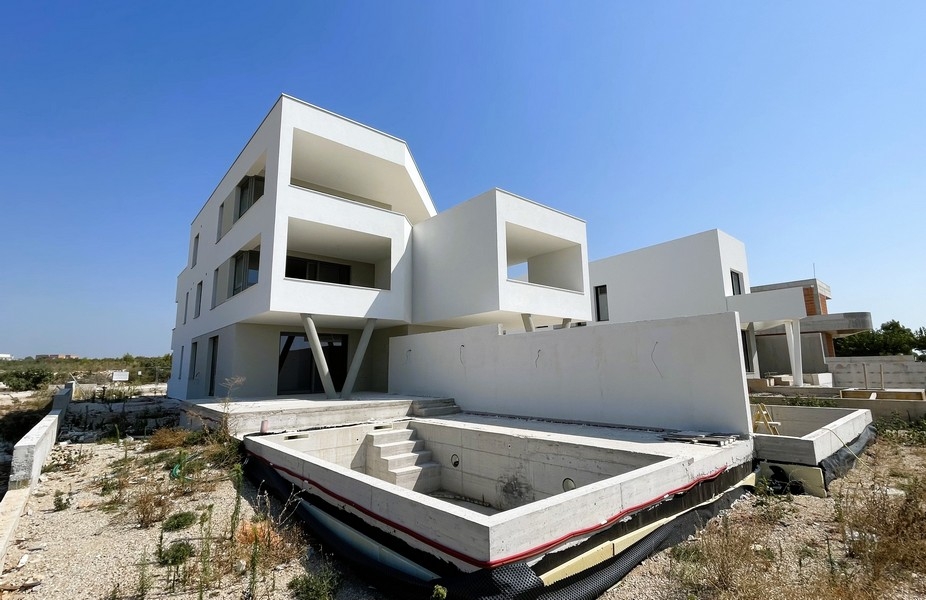 Immeuble neuf blanc avec bassin de piscine en gros œuvre devant