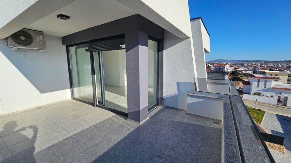 Terrasse avec dalles foncées et porte coulissante vers la pièce