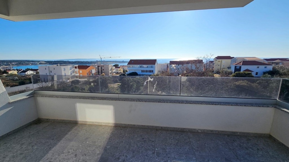 Loggia avec garde-corps en verre et vue sur le village jusqu'à l'eau